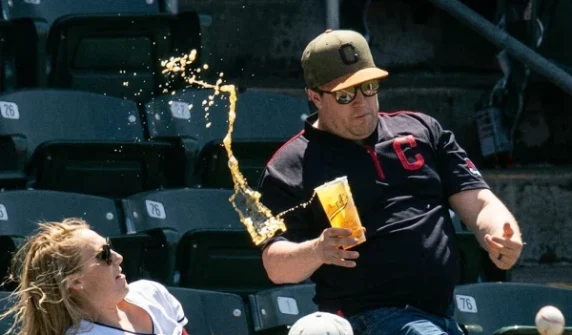 A spectator's attempt to catch a ball at a baseball match cost a woman sitting in the stands a lot of money.