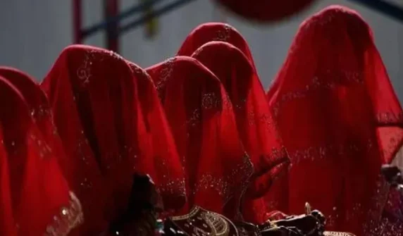 بھارت کی ریاست مدھیہ پردیش میں شادی کے نام پر مبینہ فراڈ کا انوکھا واقعہ سامنے آیا ہے، جہاں 40 سے زائد افراد دولہا بن کر اجتماعی شادی کی تقریب میں پہنچے، تاہم دلہنیں تقریب میں نہ پہنچیں۔ غیر ملکی خبر ایجنسی کے مطابق متاثرہ افراد کو ایک شخص نے خود کو شادی کے لیے رشتے کروانے والا شخص ظاہر کر کے دھوکا دیا۔ متاثرین میں شامل ابھشیک ورما کے والدین بھی اپنے بیٹے کے لیے دلہن تلاش کر رہے تھے، جب قریبی گاؤں کے ایک شخص نے ان سے رابطہ کر کے رشتہ کروانے کی پیشکش کی۔ مبینہ میچ میکر نے خاندانوں کو بتایا کہ انہیں صرف تصویروں کے البم میں سے ایک یتیم لڑکی کا انتخاب کرنا ہوگا اور اجتماعی شادی میں شرکت کے لیے تقریباً 200 ڈالر ادا کرنا ہوں گے۔ رپورٹ کے مطابق مئی کے آخر میں شادی کے روز تقریباً 40 دولہے، جن میں ابھشیک ورما بھی شامل تھا، صبح 8 بجے شادی کے لباس میں تقریب میں پہنچ گئے، تاہم کئی گھنٹے انتظار کے باوجود کوئی دلہن وہاں نہ پہنچی۔ شام تک دولہوں کو اندازہ ہوگیا کہ وہ مبینہ طور پر فراڈ کا شکار ہوچکے ہیں۔ پولیس افسر کے مطابق متاثرہ افراد کی عمریں 20 سے 40 سال کے درمیان ہیں اور ان میں زیادہ تر افراد دیہی علاقوں سے تعلق رکھتے ہیں۔ ان کا کہنا ہے کہ شرمندگی کے باعث کئی دیگر متاثرین نے ممکنہ طور پر پولیس سے رابطہ نہیں کیا۔ Bizarre wedding scam in India